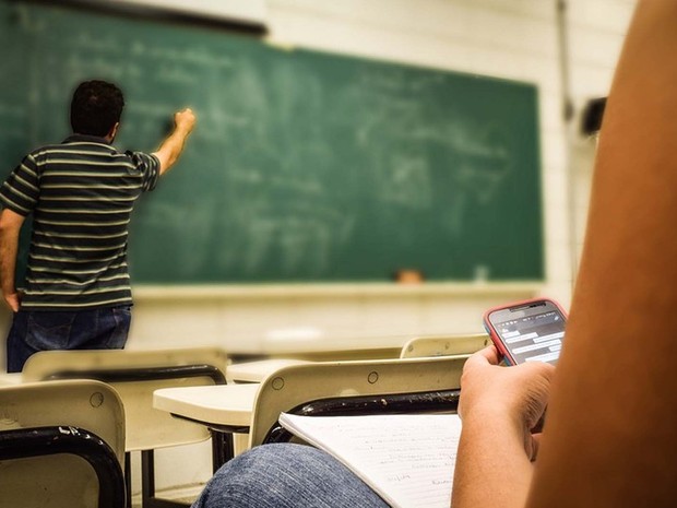 Aluno no celular enquanto professor escreve no quadro (Foto: Pixabay/Reprodução) Aluno no celular enquanto professor escreve no quadro (Foto: Pixabay/Reprodução)