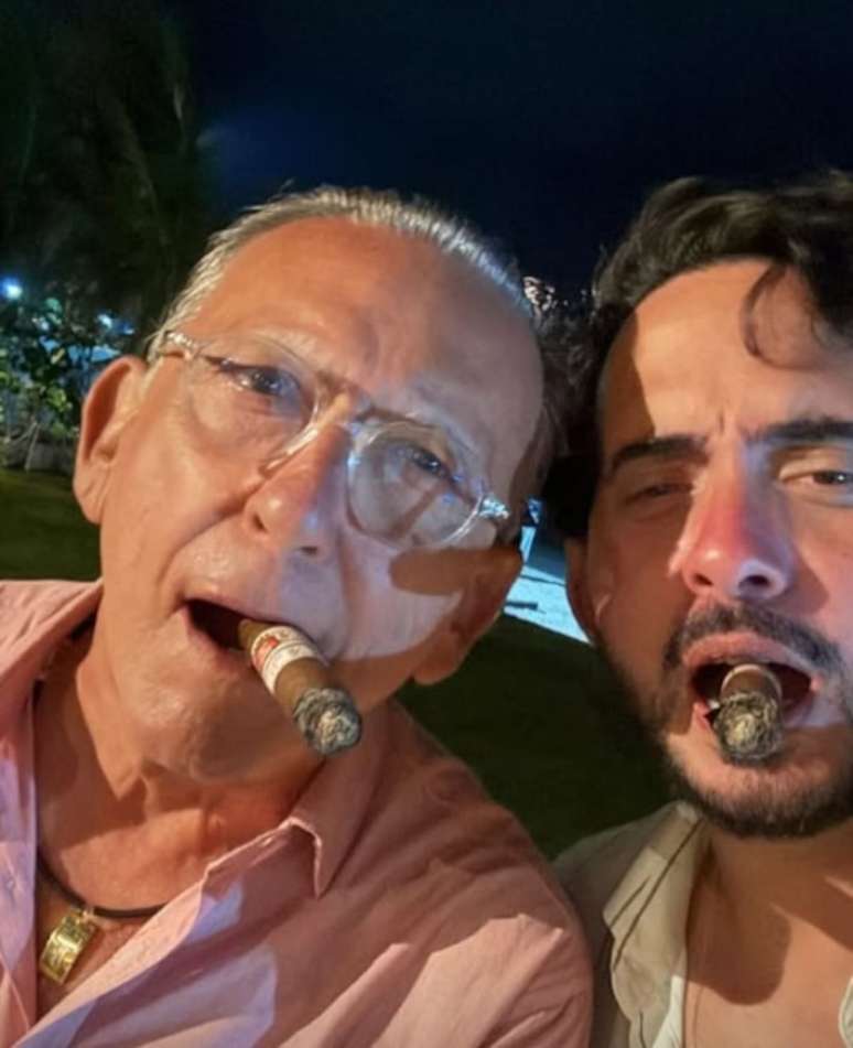 Galvão Bueno fuma charuto ao lado de empresário durante comemoração do ano-novo, em Pernambuco.